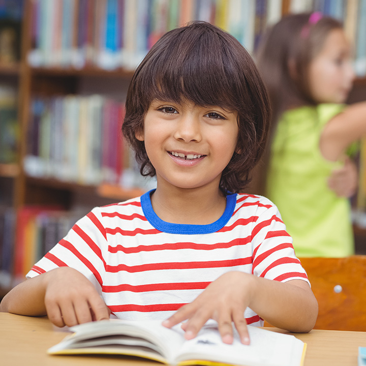 Boy looking up as he is reading a book